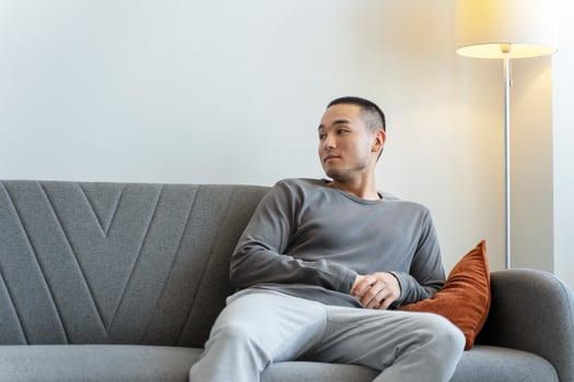 Young man relaxing on sofa at home looking away photo