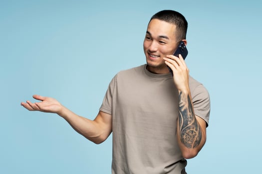 Young man gesturing while having phone conversation on blue background photo