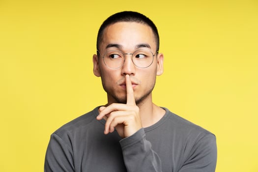Young man making silence gesture with finger on lips photo