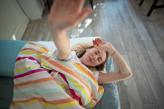 Relaxed woman closes hand and want to stay in bed in morning. Early wake up, sleep interruption photo