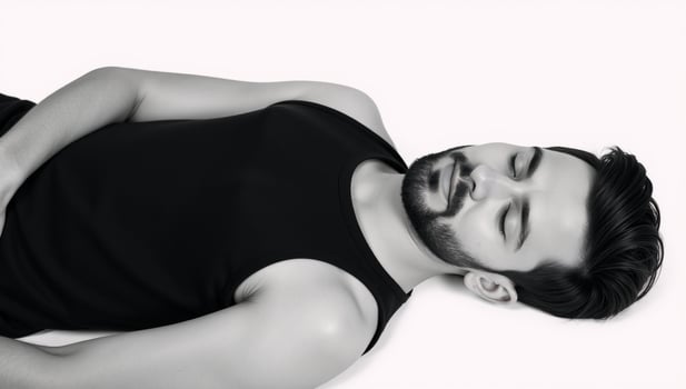 A black bearded teen sleeps or relaxes in a black tank top against an isolated white background photo