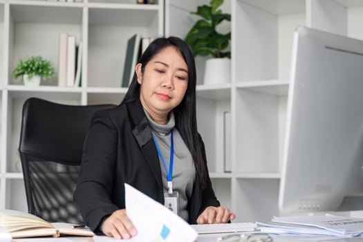 Middle-Aged Business Woman Working at Desk in Modern Office Environment with Documents and Computer photo