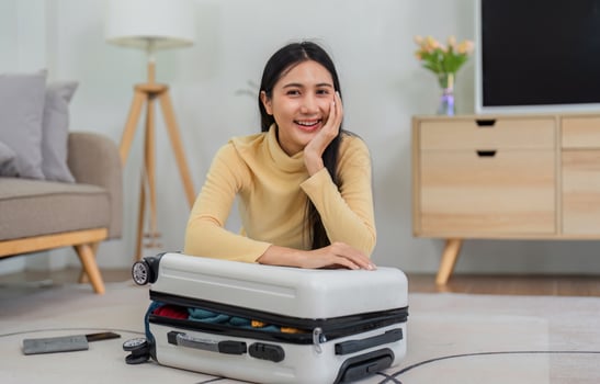 Young Woman Packing a Suitcase at Home, Preparing for a Trip, Smiling and Excited for Travel Adventure photo