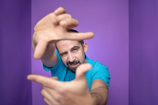 Young handsome man doing frame using hands palms and fingers, over purple background photo