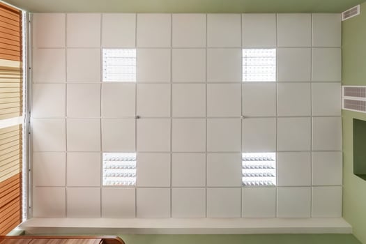 cassette stretched or suspended ceiling with square halogen spots lamps and drywall construction in empty room in house or office. Looking up view photo