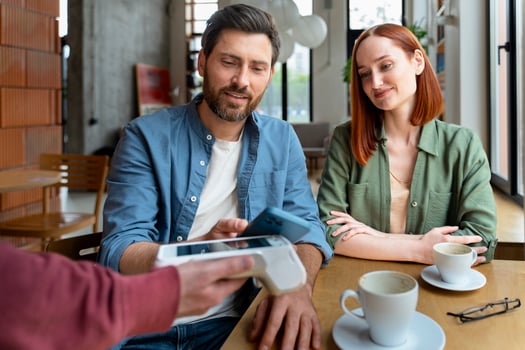 Couple making a contactless payment using a smartphone in a cafe photo