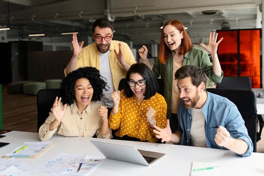 Excited multiethnic business team celebrating success looking at laptop photo