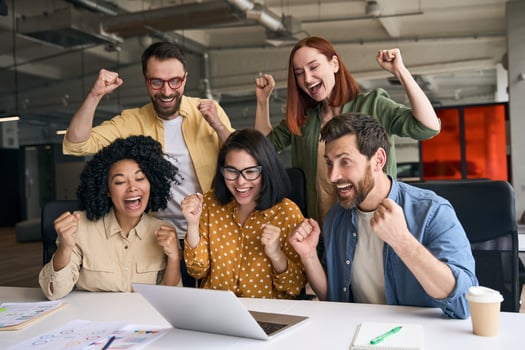 Excited business team celebrating success looking at laptop in office photo