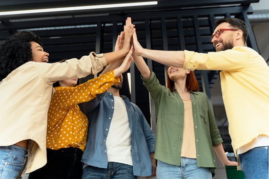 Group of diverse people giving high five together in office photo