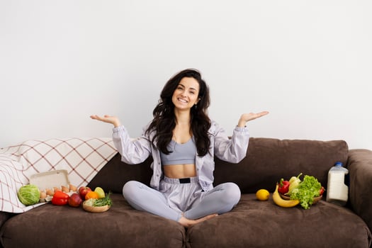 Young woman presenting healthy food options while sitting on sofa photo