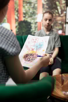 Psychologist reviewing scary sinister sketches by a troubled adolescent, displaying dangerous, unsettling emotions. The drawings suggest depression, aggression and social disorders. Close up. photo