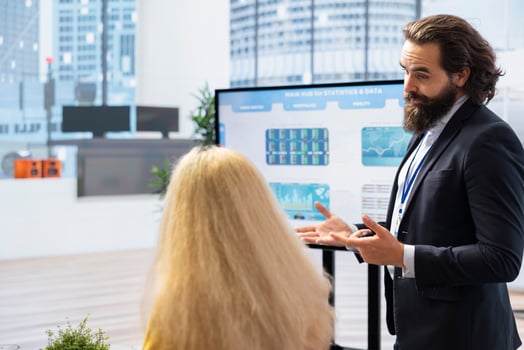 Broker investor in office offering financial advice to clients, looking at stock exchange volatility on big screen. Financial advisor analyzing market shares growth with mother and daughter photo