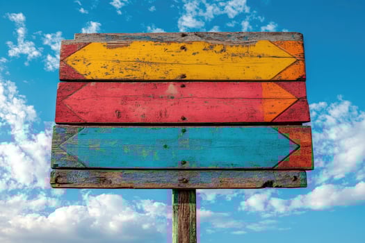 Three colorful wooden arrows pointing in different directions on a signpost photo