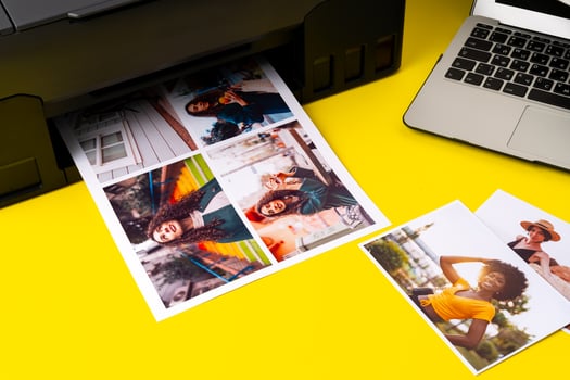 Printer printing colorful photos of people close up, yellow background