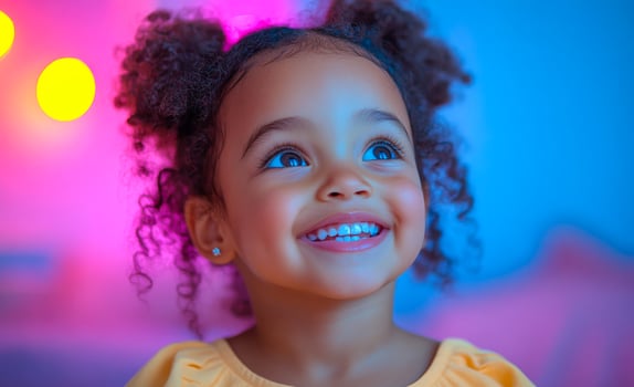 Smiling child with curly hair in bright room. A young girl with curly hair beams with happiness, surrounded by vibrant lights in a playful setting. photo