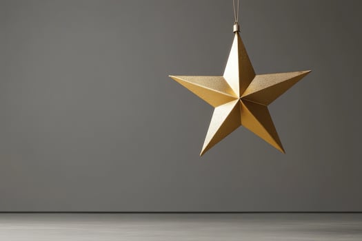 A Golden Star Ornament Hanging Against a Grey Background photo