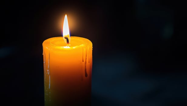 Burning candle flame in the dark. Concept of memory, hope, grief, and remembrance. photo