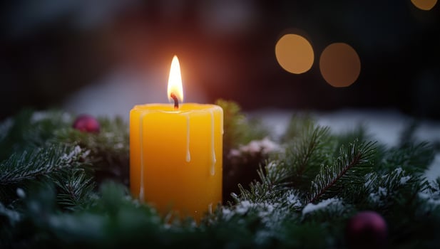 Glowing candle in Advent wreath during snowfall. Concept of Christmas, winter holidays, and festive season. photo