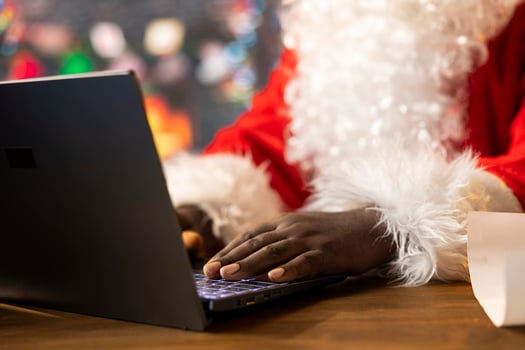 Father Christmas is browsing websites on his laptop and checking holiday gift lists from his North Pole cabin. The festive season is alive with online magic and holiday traditions. photo