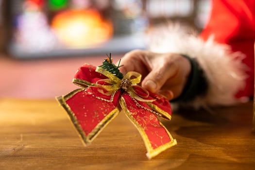 Santa wraps a festive gift box by the fire in his North Pole log workshop, surrounded by holiday lights. Father Christmas prepares presents and surprises for the x mas holiday. Close up. photo