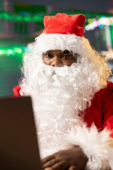 Father Christmas is navigating the web checking on children wish lists using his laptop. Festive North Pole cabin is filled with holiday cheer and online activity this x mas, checking the world map. photo