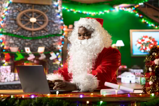 Father Christmas is navigating the web checking on children wish lists using his laptop. Festive North Pole cabin is filled with holiday cheer and online activity this x mas, checking the world map. photo
