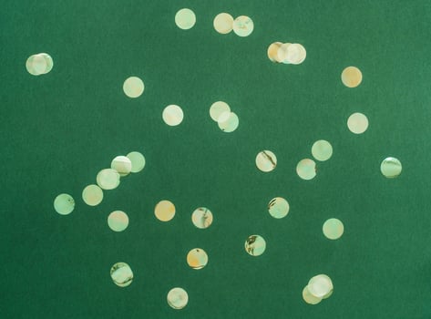 Festive flat-lay arrangement featuring green glittery baubles scattered across green background photo