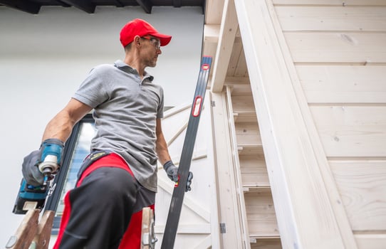 A Carpenter Using a Level Tool While Working on Wooden Structure in a Residential Area photo