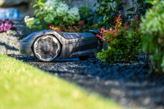 Robotic Lawn Mower Working on a Meticulously Landscaped Garden During Bright Afternoon Light photo