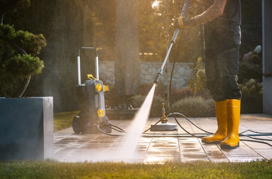 A Person Power Washing a Patio With a Pressure Washer in a Sunny Outdoor Setting photo