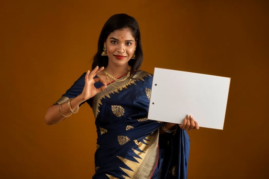 A young Indian girl or woman holding a signboard in her hands on a brown background. photo