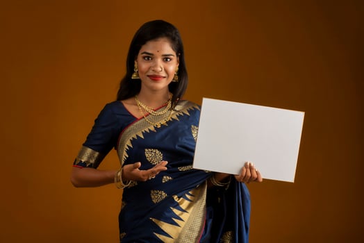 A young Indian girl or woman holding a signboard in her hands on a brown background. photo