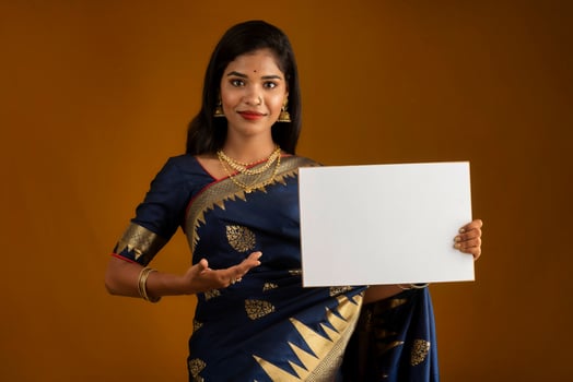 A young Indian girl or woman holding a signboard in her hands on a brown background. photo
