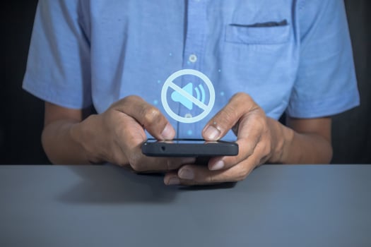 Man holding a mobile phone with mute sound or silent mode symbol photo