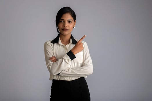 Young smiling girl pointing fingers to copy space on a grey background photo