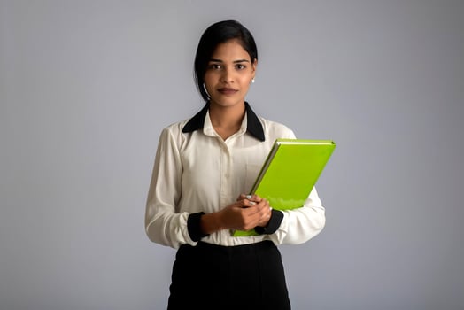 Pretty young girl holding book and posing on grey background photo
