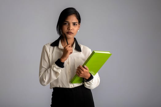Pretty young girl holding book and posing on grey background photo