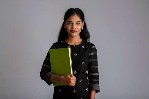 Pretty young girl holding book and posing on grey background photo