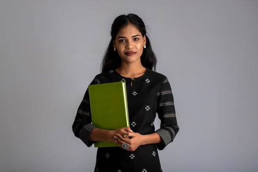 Pretty young girl holding book and posing on grey background photo