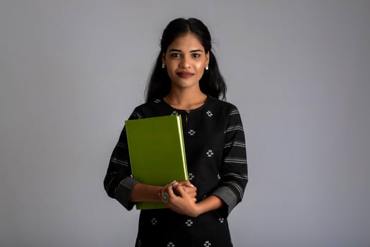 Pretty young girl holding book and posing on grey background photo