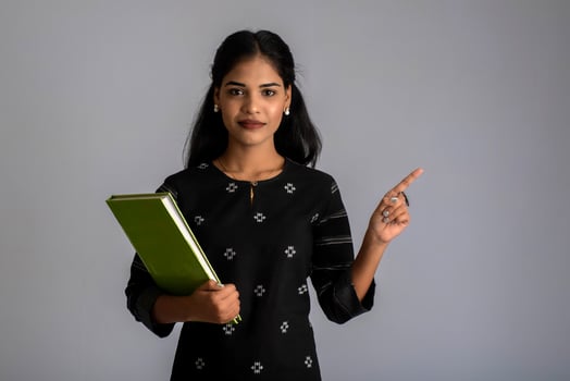 Pretty young girl holding book and posing on grey background photo