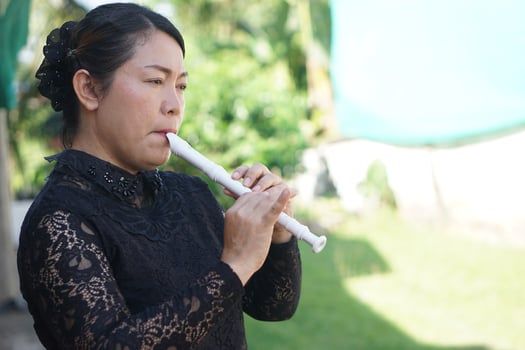 Asian woman flutist, musician is playing a recorder flute. Concept, music blowing with mouth, control with fingers on holes of flute for melody and rhythm. Mouthpiece musical instrument. photo