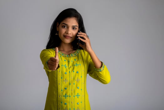 Young girl using mobile phone or smartphone on gray background photo