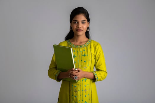 Pretty young girl posing with the book on grey background photo
