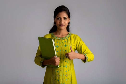 Pretty young girl posing with the book on grey background photo