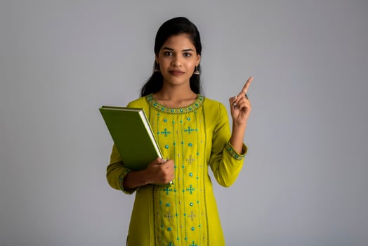 Pretty young girl posing with the book on grey background photo