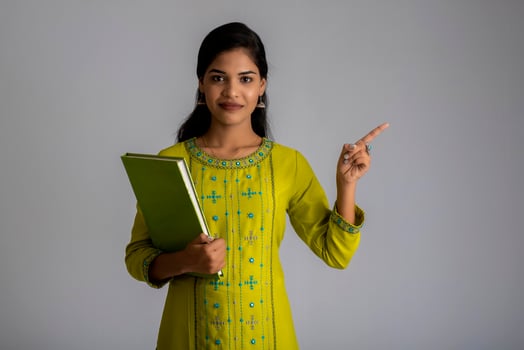 Pretty young girl posing with the book on grey background photo