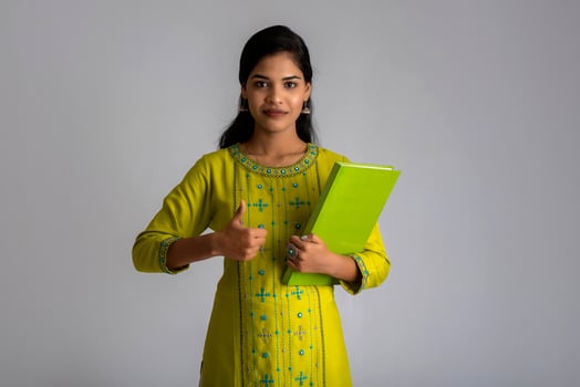 Pretty young girl posing with the book on grey background photo