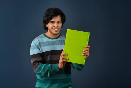 Young happy man holding and posing with the book on background. photo
