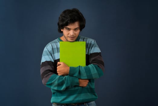 Young happy man holding and posing with the book on background. photo